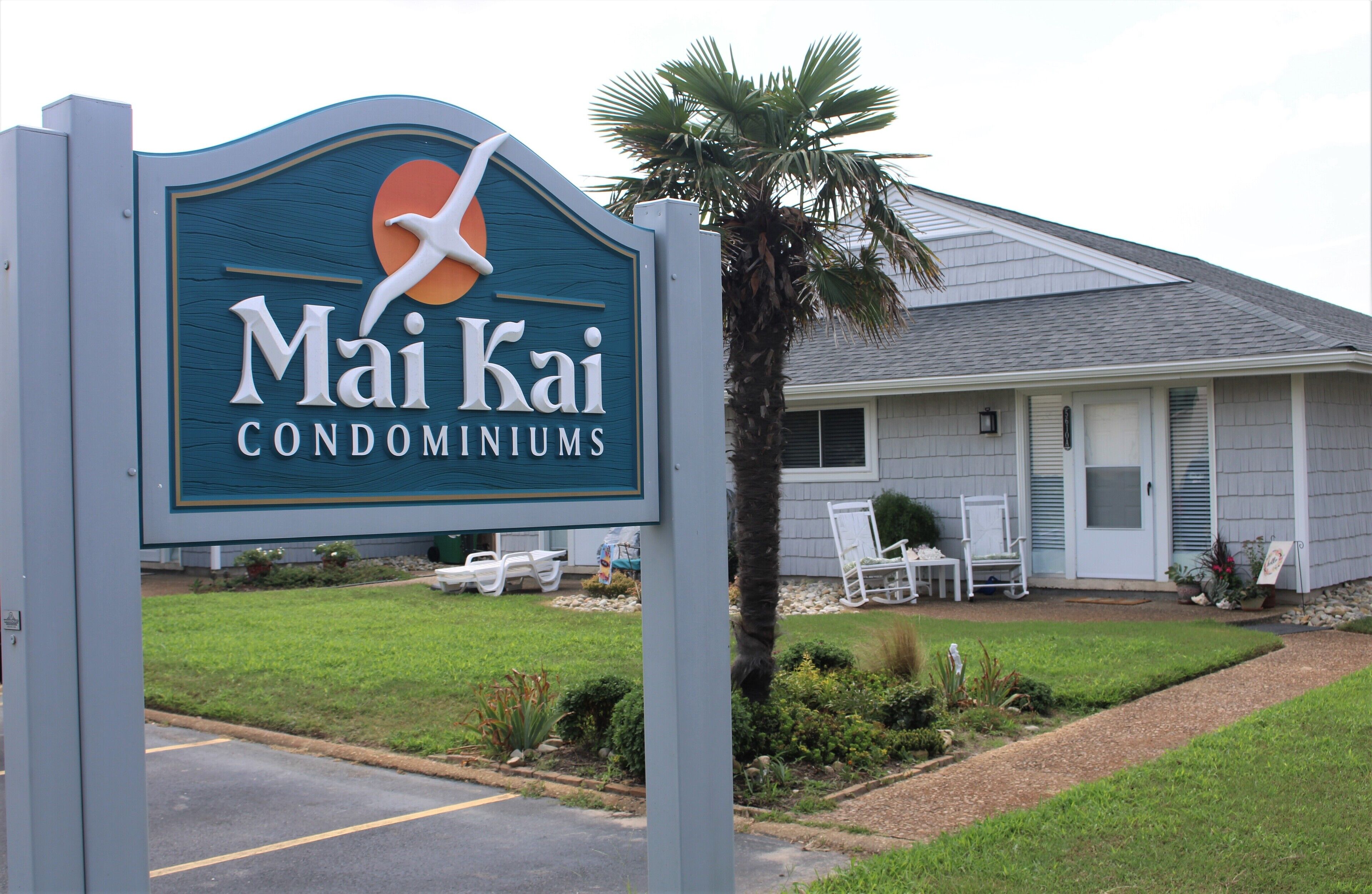 Mai Kai Condominiums sign beside a ground-floor unit and palm
